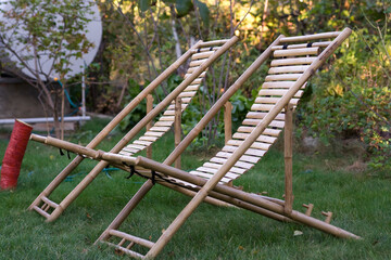 Two bamboo deck chairs on the green grass