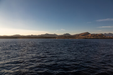 Obraz premium Beautiful blue sea. Sunny evening. Mountains and desert on the coast. Colorful sea landscape.
