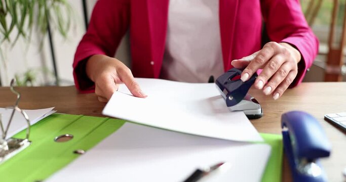 Businesswoman fastening important papers with hole punch closeup 4k movie slow motion 