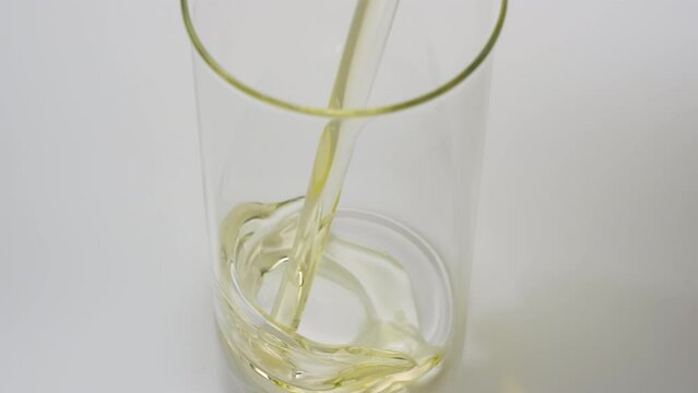 Crane shot of olive oil is being poured into empty beaker on grey background | Abstract anti-aging cosmetics ingredients formulating concept