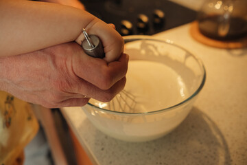 a man's and a child's hand holds a dough whisk