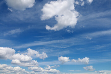 Blue sky with clouds. Spring or summer background. 
White clouds on the blue sky have a complex...