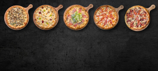 Pizza in assortment, on a wooden board, on gray concrete
