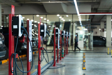 Fototapeta premium Electric car charging station for charge EV battery. Plug for vehicle with electric engine. EV charger. Clean energy. Charging point at car parking lot. Green power. Future transport technology.