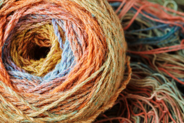 Ball of yarn from pure organic sheep's wool on an unwound skein of woolen threads. Rainbow color.