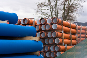 Plastikowe rury kanalizacyjne i do wody składowane na drewnianych paletach . 