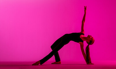 Fototapeta na wymiar teenage girl in a tight black costume dancing a modern contemporary contemporary dancer isolated on a background in neon light.