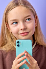 Charming attractive european little girl thinking before sending voice message on smartphone. Communication and new technologies concept. adorable american teenage girl isolated on purple