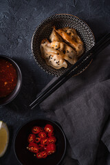 Fried japanese  dumplings gyoza with soy sauce,chili and chopsticks on a black wooden background, Top view. Selective focus.
