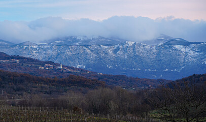 Fototapeta na wymiar Winter landscape of European town over the snow mountains with low clouds