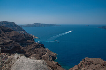 Boats go by the cliffs of Santorini on a sunny day