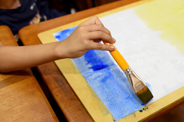 girl drawing with watercolor paints on white paper.Close-up.Classroom.Waldorf pedagogy