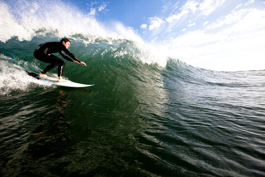 A male surfer does a bottom turn while surfing in Malibu.