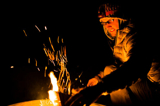 A male climber reads a guidebook by a campfire in Joshua Tree, California.