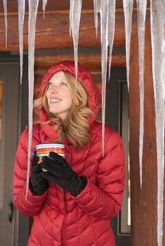 A smiling young woman braces against the cold with a mug of tea in Jackson Hole, Wyoming.