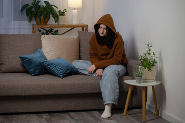 sad teenager girl sitting on couch indoor at night