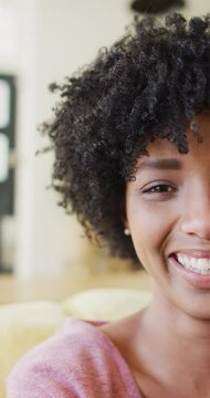 Vertical half face video portrait of laughing biracial woman with afro, with copy space
