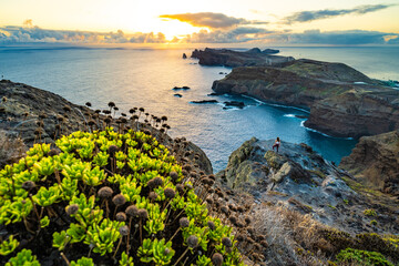 Woman enjoys panoramic view from a steep cliff over the seascape and along the rugged foothills of...