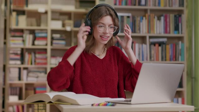 Young woman listening to audio using headphones in library