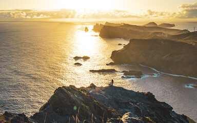 Sitting woman enjoys panoramic view from view point on a steep cliff over the seascape and along...