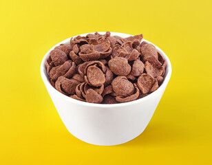 Chocolate cereals in white bowl. Chocolate flavored corn flakes. Wheat. Cocoa. Crispy. Crunchy. Breakfast. Snack. Granola. Oat.