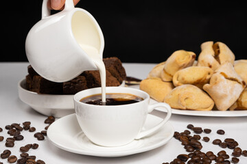 Cream from the milk jug is poured into coffee, making coffee with cream, cappuccino.