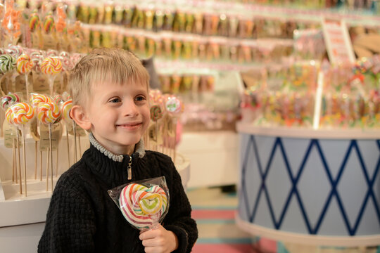 A Boy Holding A Big Candy In His Hands In A Candy Store