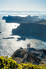 Backpacker couple enjoying the view from a vantage point on a steep cliff overlooking the rugged...