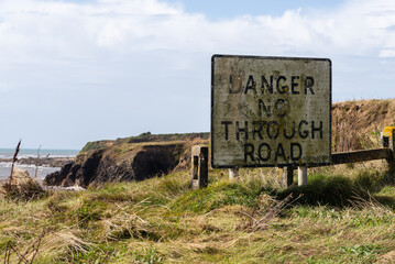 sign informing about the danger of the cut road over the cliffs.