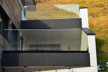 Moderner Balkon mit Sturzschutz/Sichtschutz aus Glasplatten und Metall-Geländer an einer Neubau-Hausfront