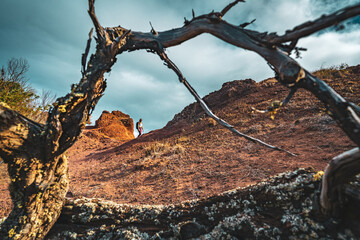 Backpacker woman enjoys hike along a steep cliff overlooking the sea and the rugged foothills of Madeira's coast in the morning. Ponta do Bode, Madeira Island, Portugal, Europe.