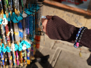 Fototapeta na wymiar a woman's hand chooses a bracelet at a street bazaar in the sunlight