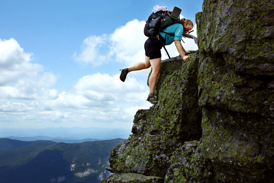 A young women hikes up a rock ledge.