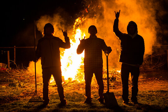 Friends stand in front of large bonfire
