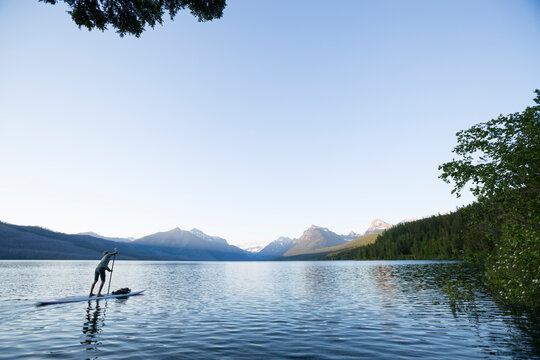 A woman up paddle boards (SUP) on Lake McDonald in Glacier National Park.