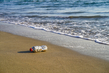 Obraz premium A bottle of cigarette butt stub on the clean beach sand near mediterranean sea and ocean, to pay attention to environmental pollution, global warming and warning, no smoking area