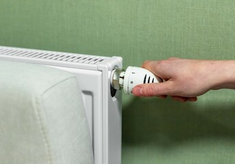 Hand adjusting radiator, turning it on or off. Heat, energy consumption at home in cold weather concept