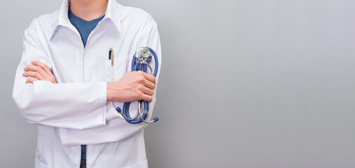 Young doctor with stetoscope closeup over grey background with copy space.