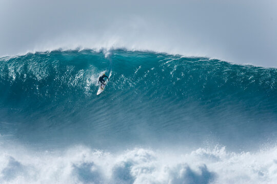 A young man surfing a huge wave at Pipeline, on the north shore of Oahu.