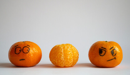 Two whole tangerines look with suspicion and fear at a peeled mandarine.  Three orange cheerful...
