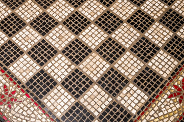 Black and white pattern on a checker board made of mosaic tiles.