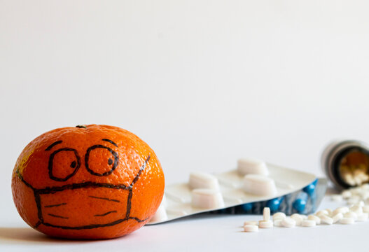 A painted face in a mask looks suspiciously at a pile of medicines.  The concept of fear of disease and mistrust of medicine. Space for text