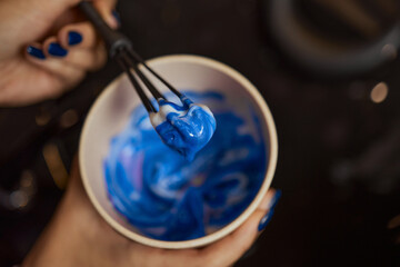 girl in white rubber protective gloves holding a brush in her hands and stirring hair dye close-up...