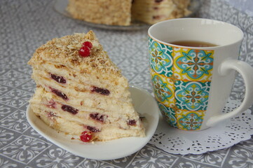 Piece of Napoleon cake with cherries  and a cup of tea.