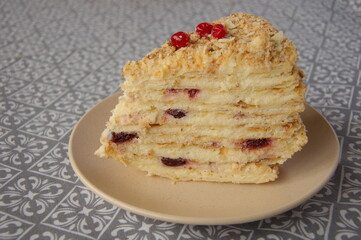 Piece of Napoleon cake on a beige plate close-up.