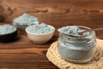 Blue spirulina powder in bowls and spoon on brown texture background. Natural vegan superfood. food supplement. place for text. Copy space.