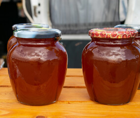 Honey in glass jars. Sale of honey in transparent glass jars at the agricultural market. Close-up. Sale of beekeeping products.