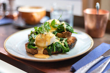 Healthy balanced breakfast with poached eggs, spinach and hollandaise sauce on toasted sourdough bread