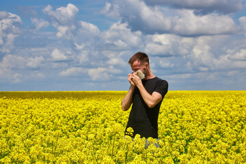 man in field blowing his nose and suffering from hay fever.