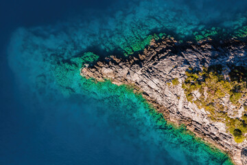 Aerial top down shot of rocky shore and turquoise water of aegean sea. static aerial shot